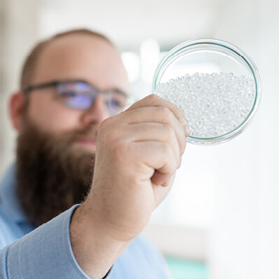Chemiemitarbeiter hält Petrischale mit Plastik in der Hand