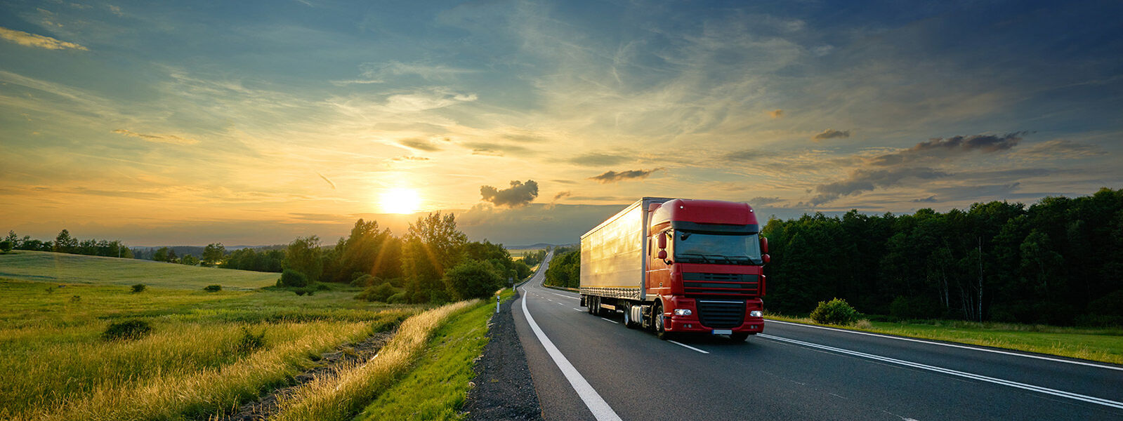 Foto eines fahrende LKW auf einer Landstraße im Sonnenuntergang